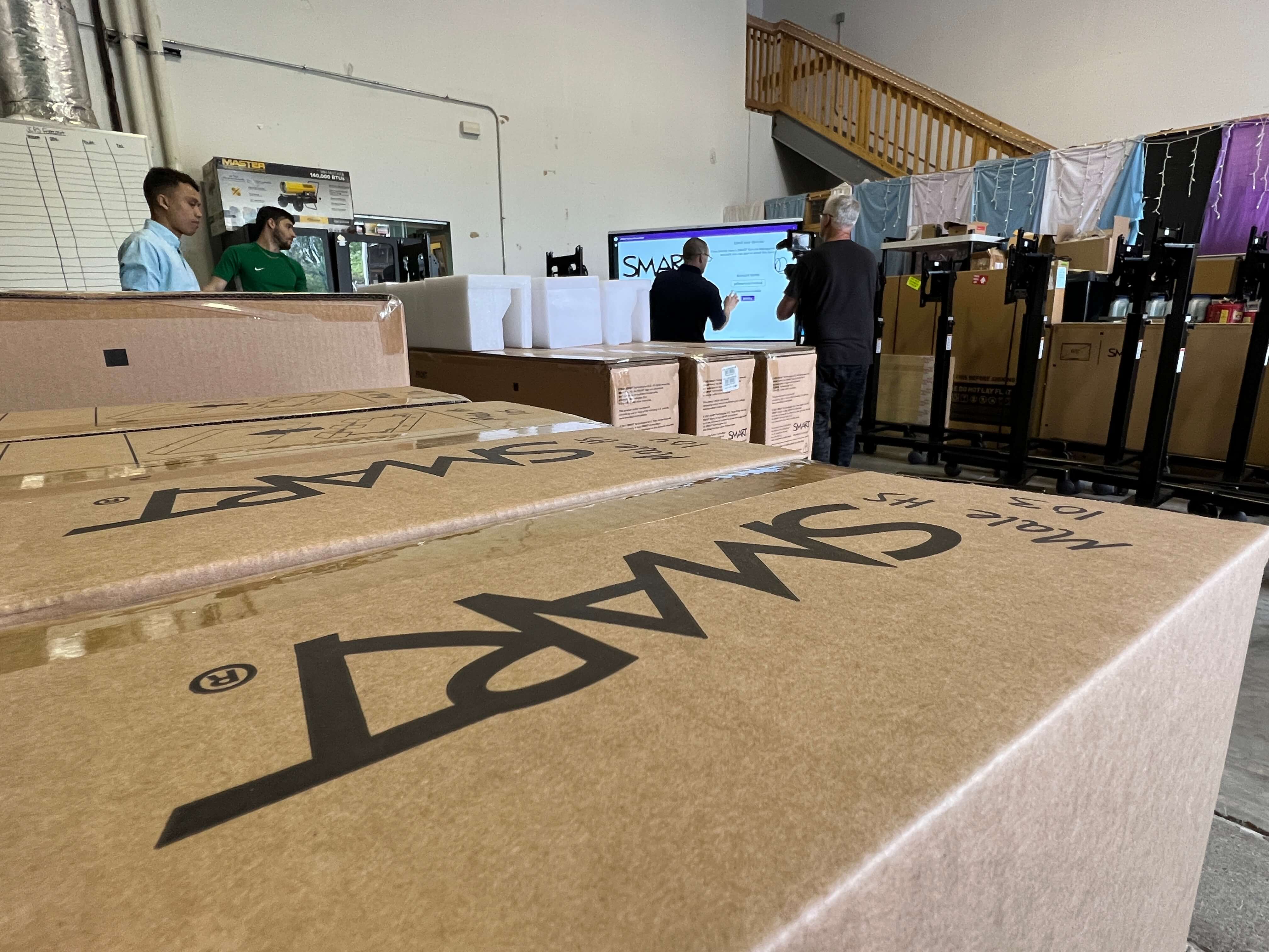 A row of 4 boxes holding SMART Boards being delivered to Newcomer Academy.