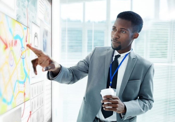 Business professional discussing project timelines and details on a SMART interactive display.