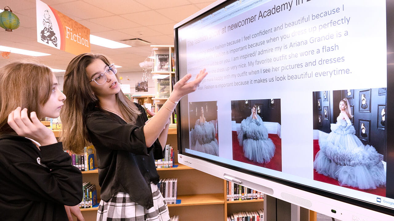 Teacher with student at a SMART Board in a library